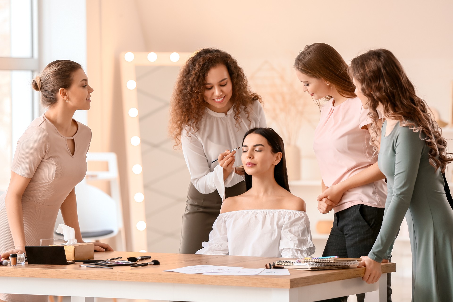 Group of beautiful women applying make up to a lady