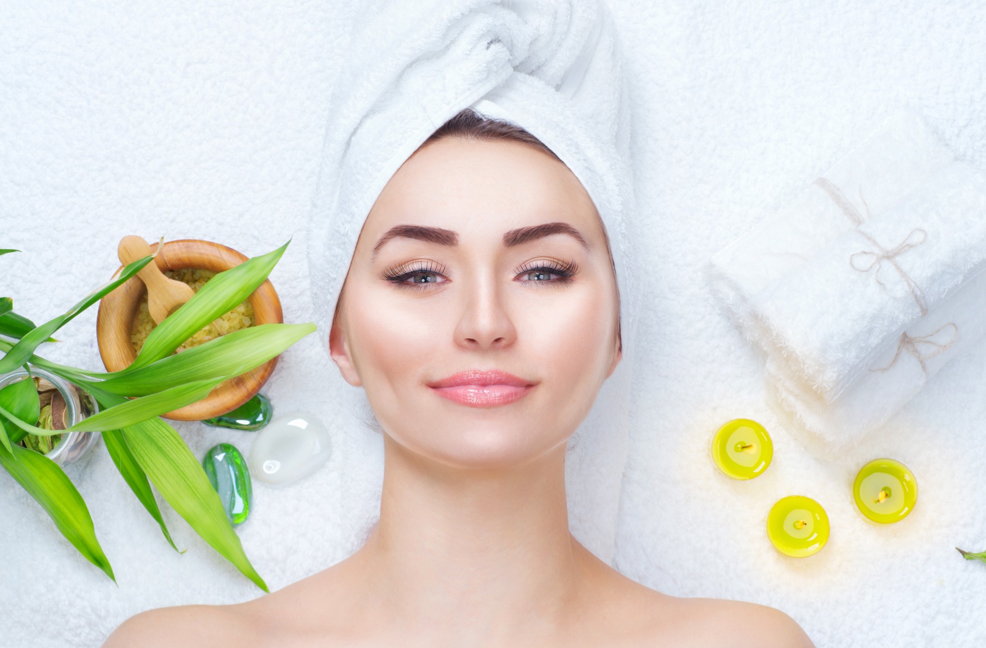Woman getting beauty facial treatment with oils and natural products around her